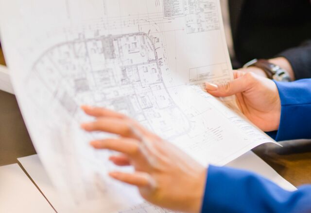 NOVIA GmbH Consulting und Baumanagement - Detailaufnahme: Frauenhand zeigt auf groß gedruckten Bauplan