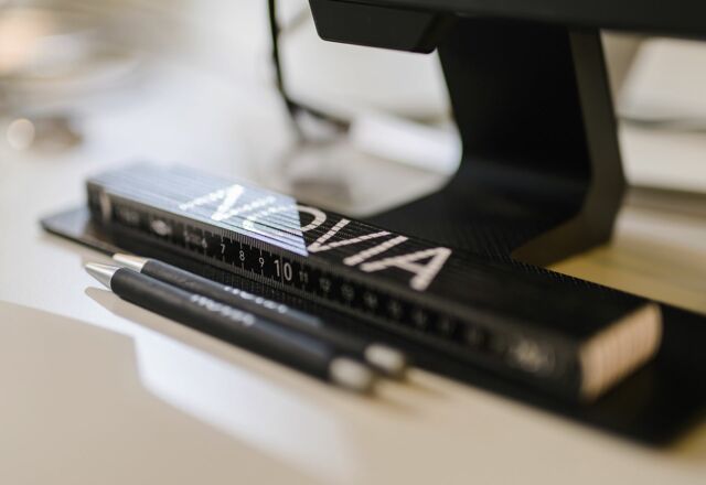 NOVIA GmbH Consulting und Baumanagement - Detailaufnahme: Schwarzer Zollstock mit NOVIA-Logo liegt auf hellem Schreibtisch.