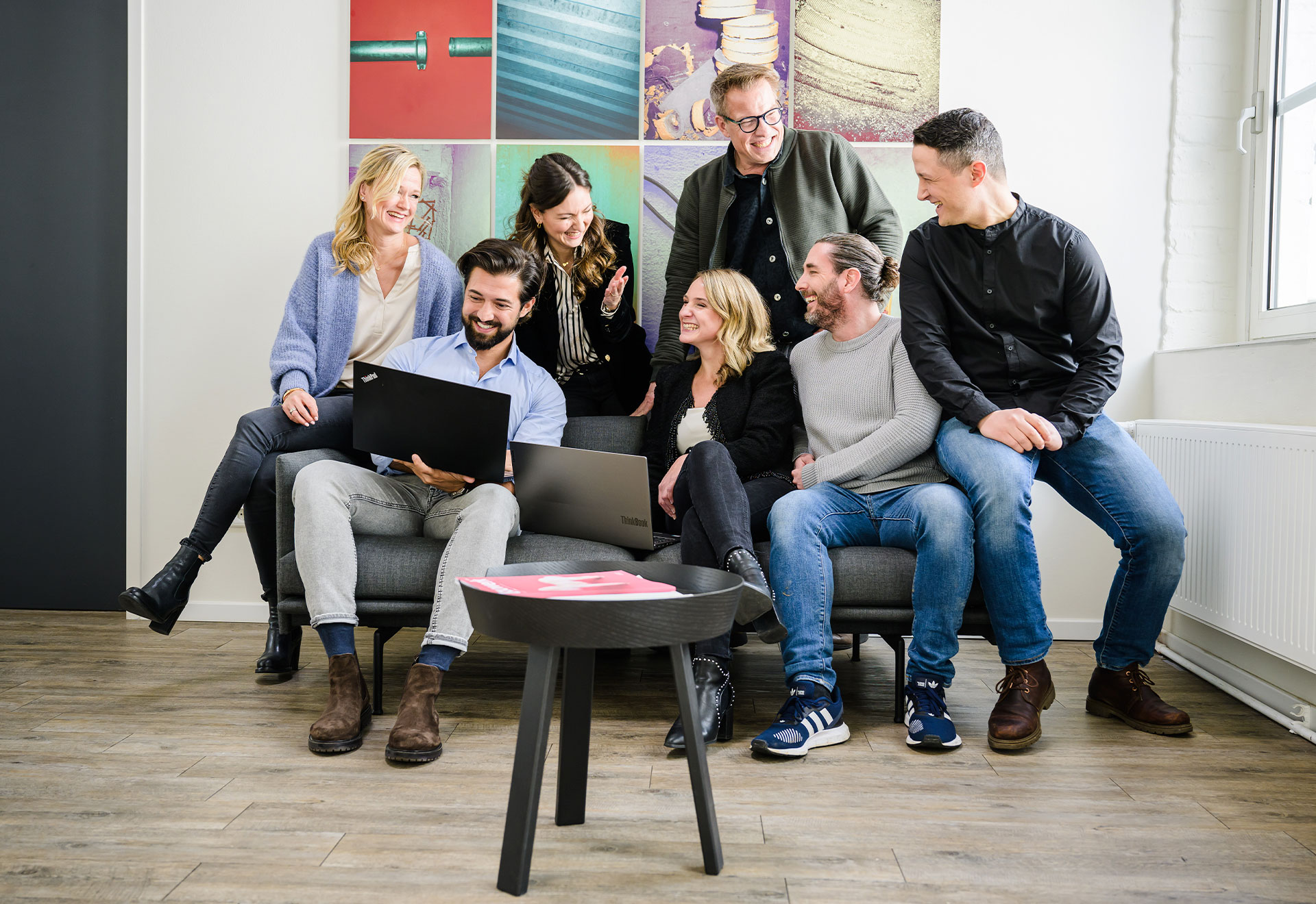 NOVIA GmbH Consulting und Baumanagement - Mitarbeiter unterhalten sich in Gruppe auf Sofa und lachen