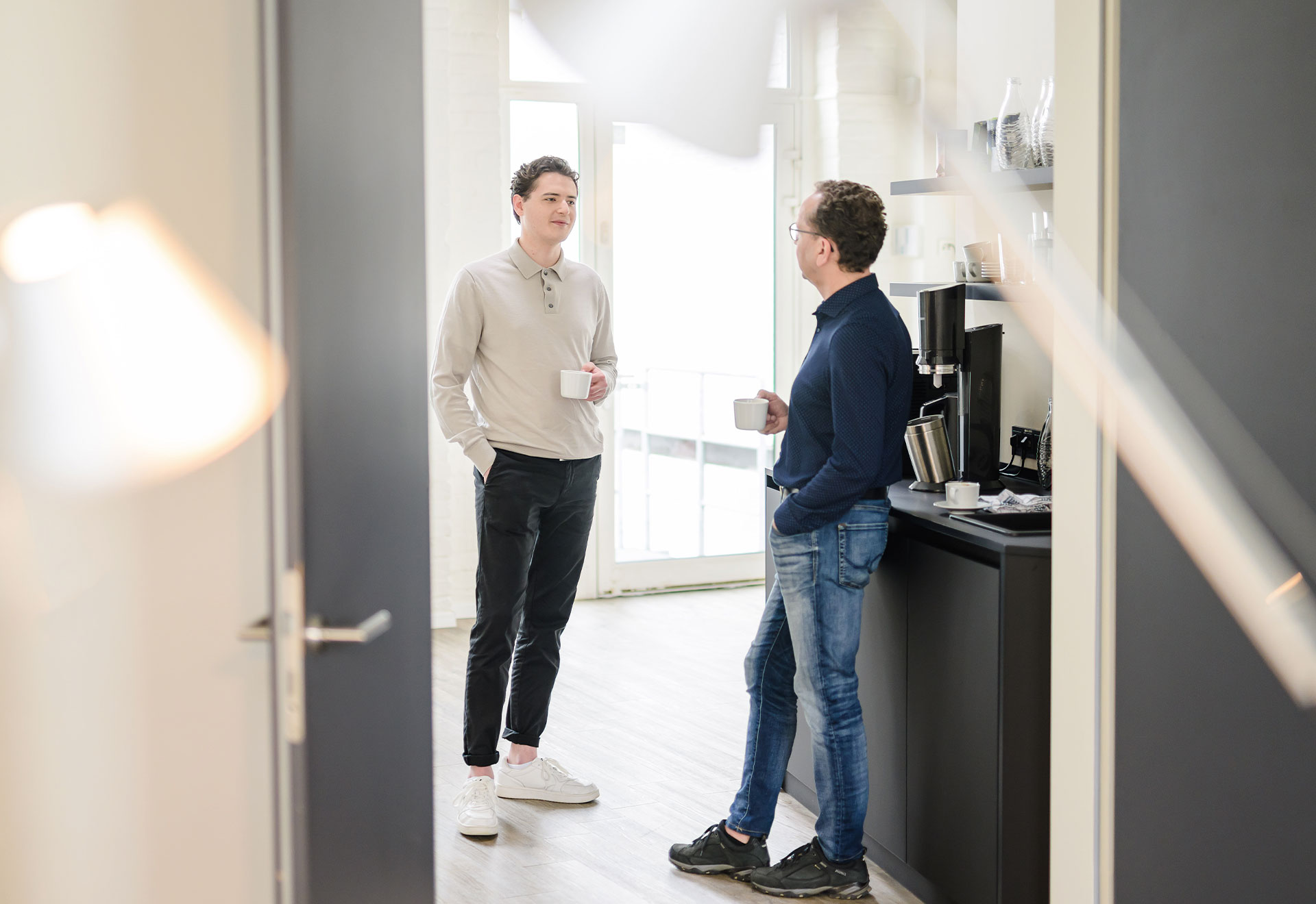 NOVIA GmbH Consulting und Baumanagement - Momentaufnahme lockeres Gespräch zweier Kollegen in der Teeküche